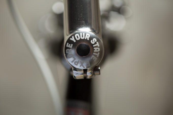 stem cap on the top of the black and metallic State Bikes 4130 Road saying "explore your state" 