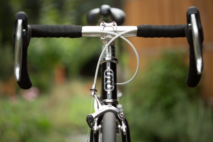 front view of a black State Bikes 4130 road bike in front of an out of focus background